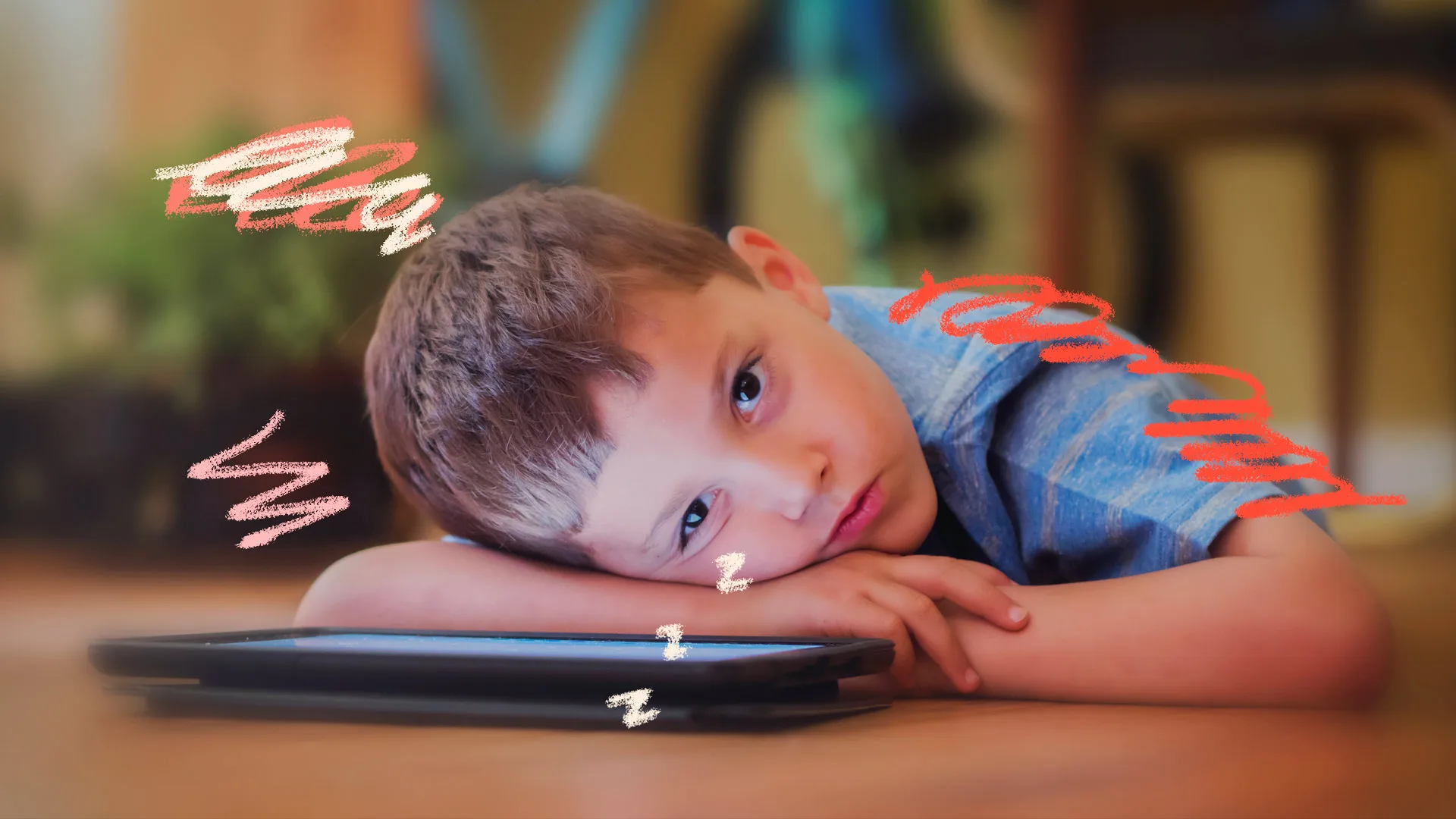 Menino deitado no chão, cansado, ao lado do tablet